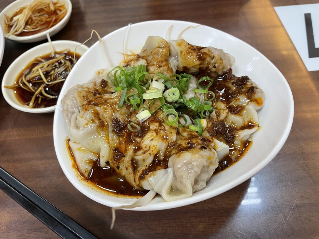 高雄 牛肉麵の名店で提供される紅油抄手。辣油とネギをかけた一品
