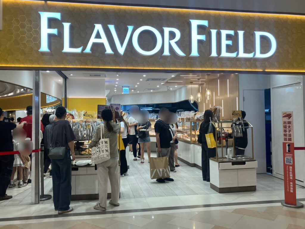 漢神巨蛋地下1階のベーカリー「FLAVOR FIELD」店頭。多くの客が並び、右側には明太子法國の出炉等候区ポールが見える。
