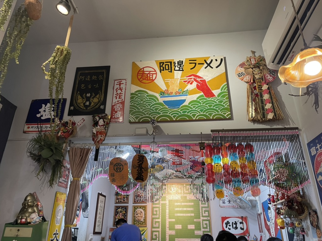高雄の麺食店「阿邊麺食(A-Bian Noodles)」の店内装飾。ラーメンの絵看板や提灯、数珠のれんが並ぶレトロな空間