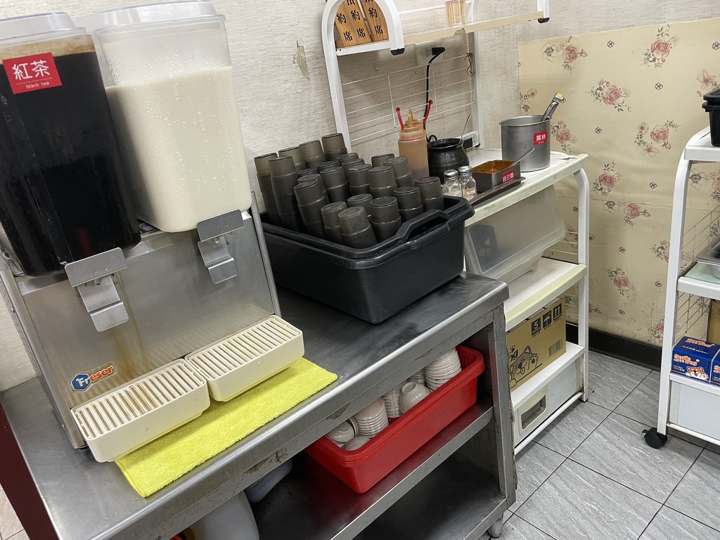 高雄 小籠包の名店「厚得福」にある無料の喫茶コーナー。紅茶と豆乳のディスペンサーと調味料が並ぶ棚