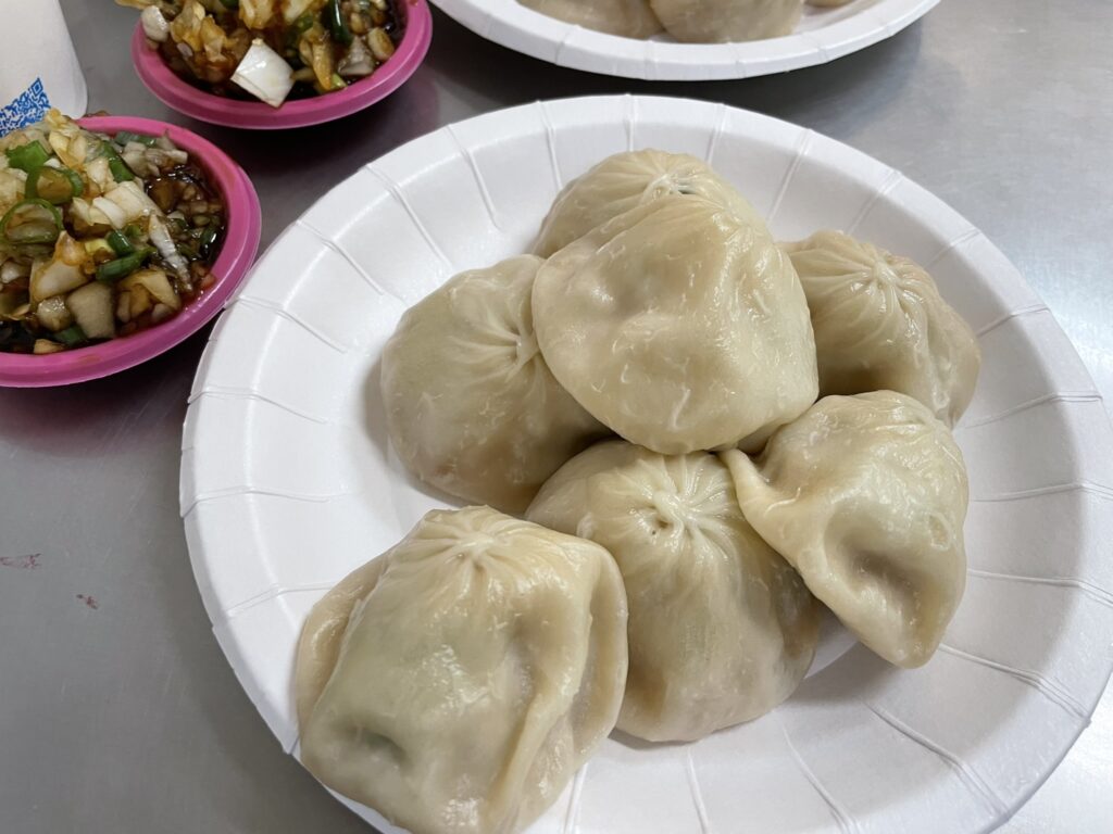 楠梓 小籠包の穴場食堂で提供される、皮が薄くジューシーな小籠包7個を紙皿に盛り付けた様子