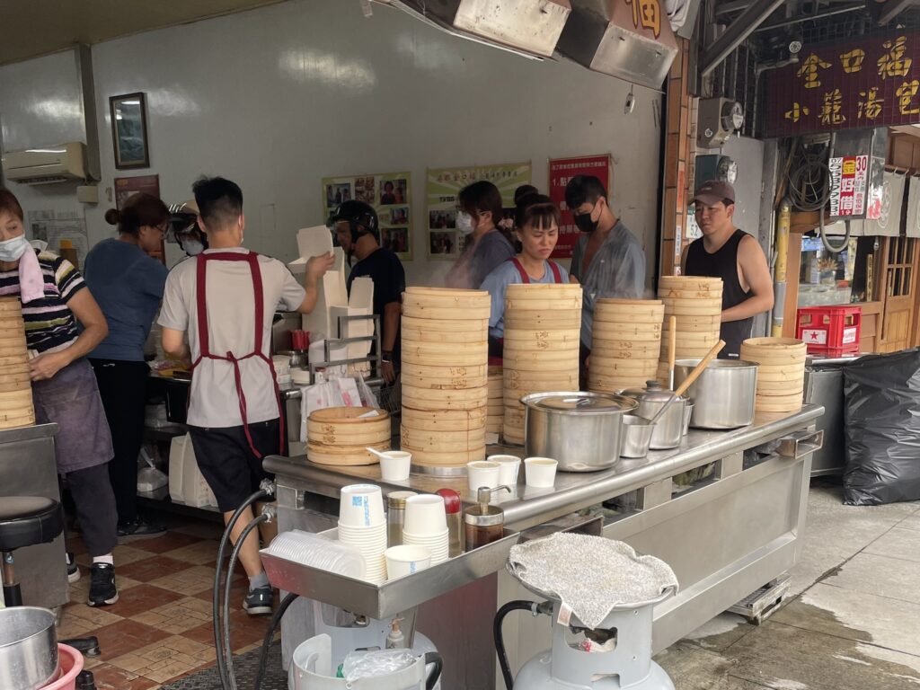 楠梓の小籠包店の厨房カウンター。積み重なった蒸籠と忙しく働く店員たちの様子