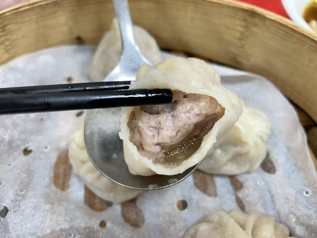 高雄 小籠包の鮮肉湯包を箸で持ち上げ断面を見せる写真、肉汁たっぷりの肉あんが確認できる